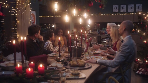 OKAL Herz des Hauses Thumbnail, eine glückliche Familie die gemeinsam an einem reichlich gedeckten Weihnachtstisch sitzen.